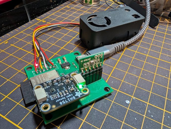 USB-Cケーブルを挿して通電中の自作センサー基板。BME280とBH1750のモジュールが挿さり、奥にSEN63Cが置かれている